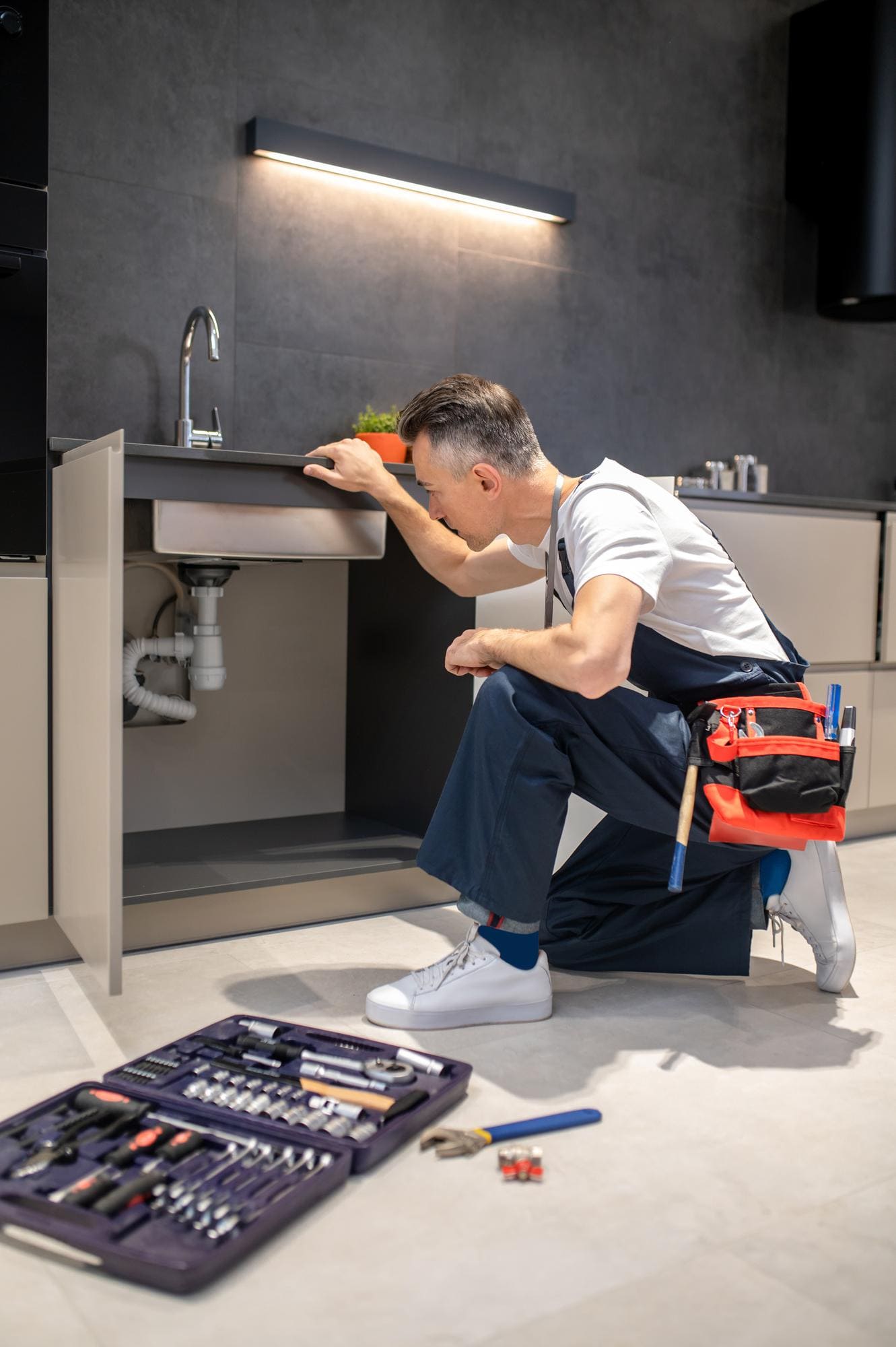 Plumbers near me inspecting under-sink plumbing